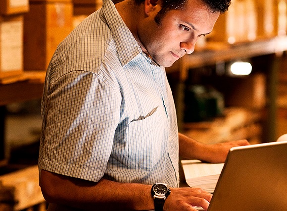 Hombre parado frente a una computadora ingreso a un sistema servicio bancario en línea.