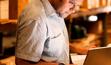 Hombre parado frente a una computadora ingreso a un sistema servicio bancario en línea.