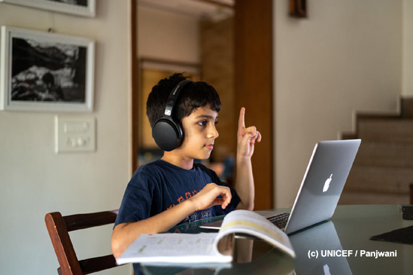Niño trabaja con laptop y audífonos.