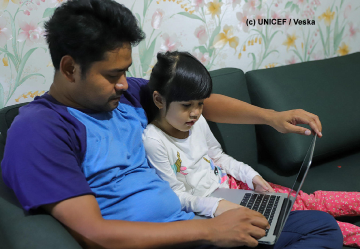 Padre e hija comparten una laptop.