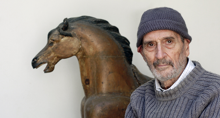 Se muestra  Vicente Rojo con una estatua de caballo detras de el.