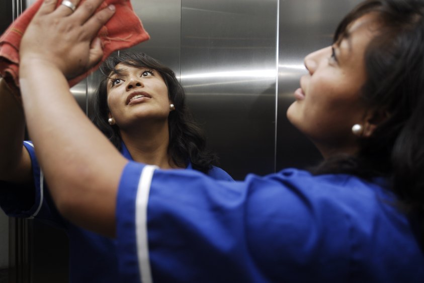 Mujer limpia un cristal de elevador