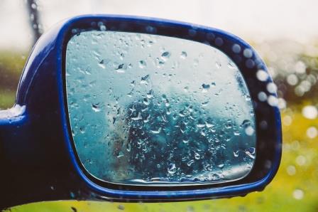 Imagen de un espejo retrovisor de un auto con gotas de lluvia