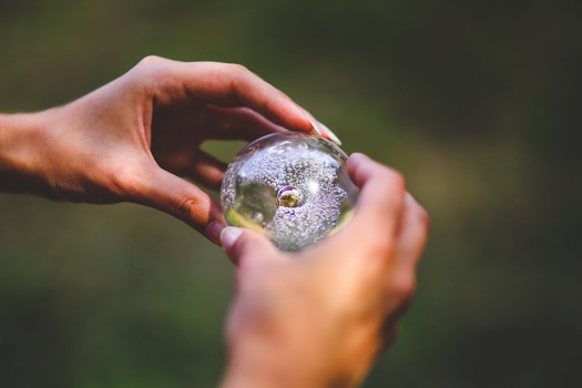 Fotografía de una persona sosteniendo una esfera de cristal