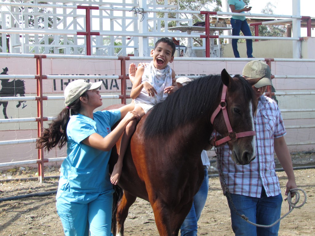 Niño con parálisis cerebral, monta a caballo recibiendo equinoterapia.