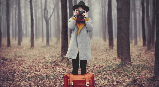 Una chica con una cámara de fotos y una maleta.