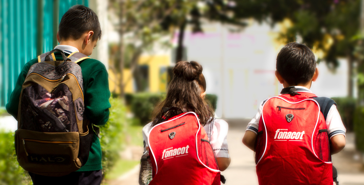 Niños caminando con sus mochilas vistos de espaldas en su regreso a clases.