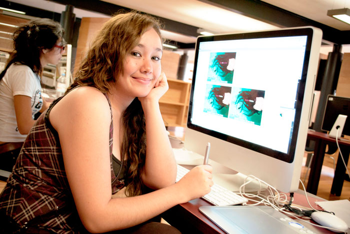 Mujer joven trabajando frente a una computadora.