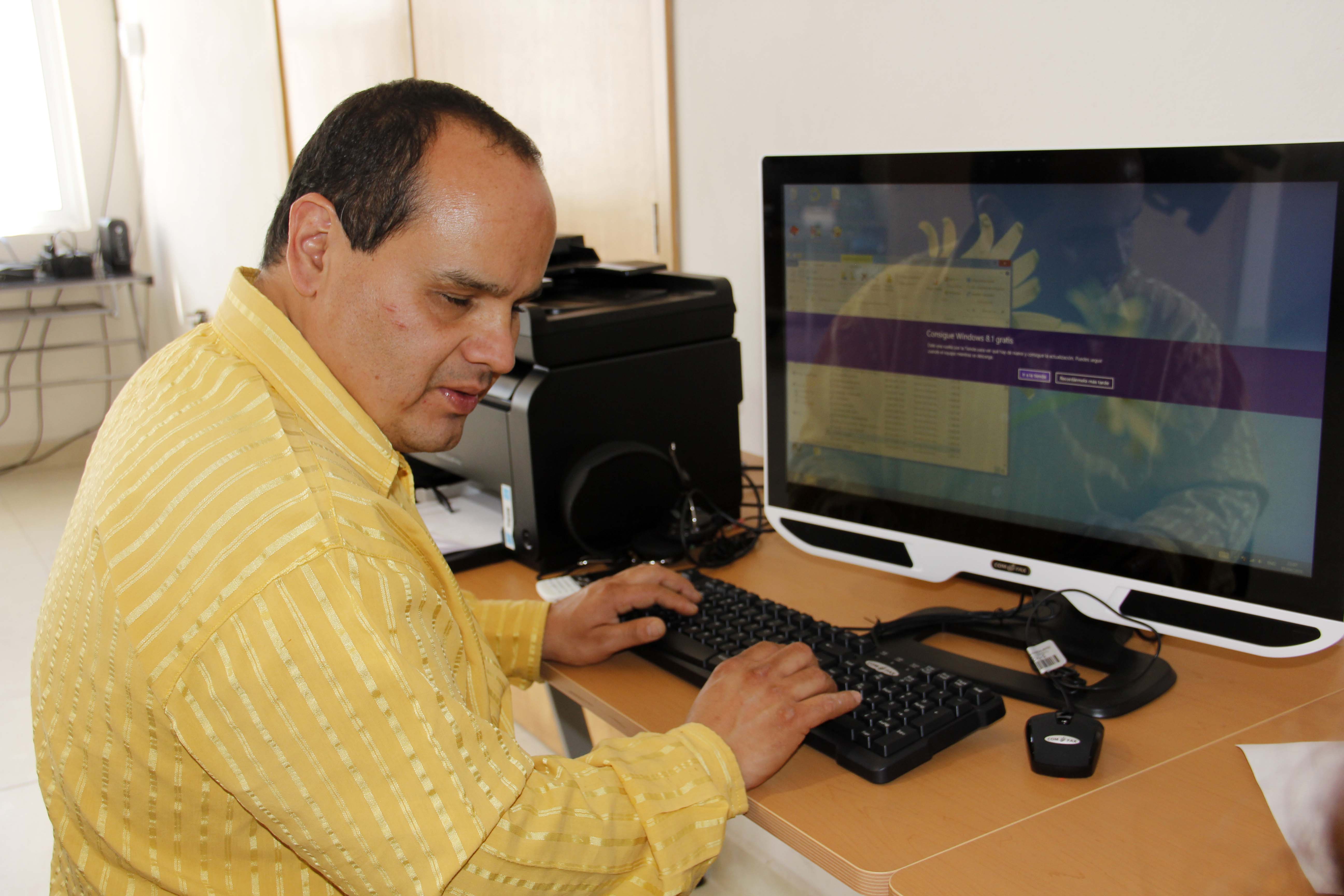 Hombre invidente trabajando frente a una computadora.