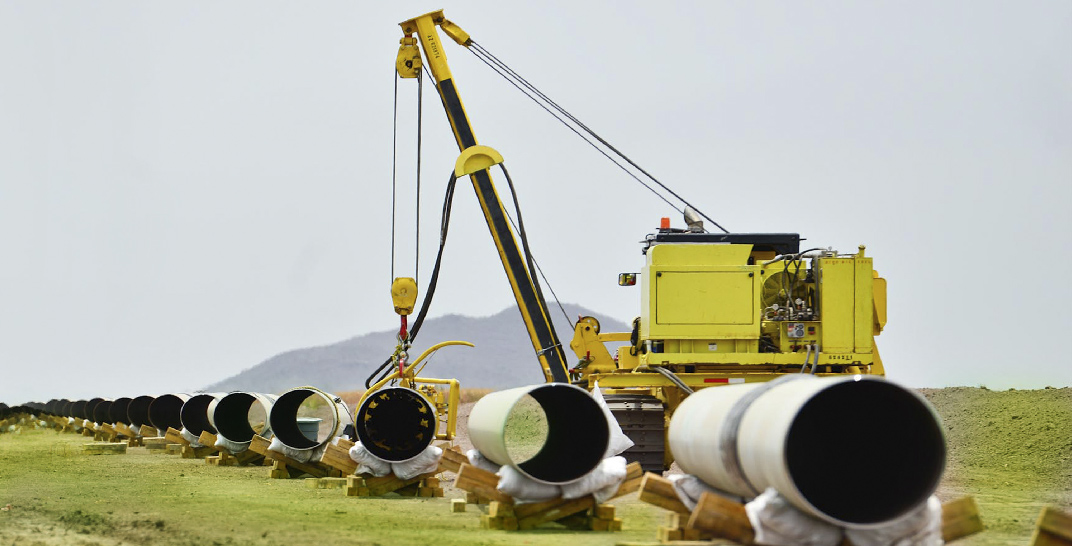 La imagen muestra una grúa acomodando tubos utilizados en los gasoductos.