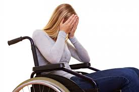 Mujer con discapacidad en silla de ruedas se cubre el rostro con las manos denotando tristeza