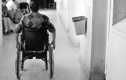 Persona en silla de ruedas avanza por un pasillo 