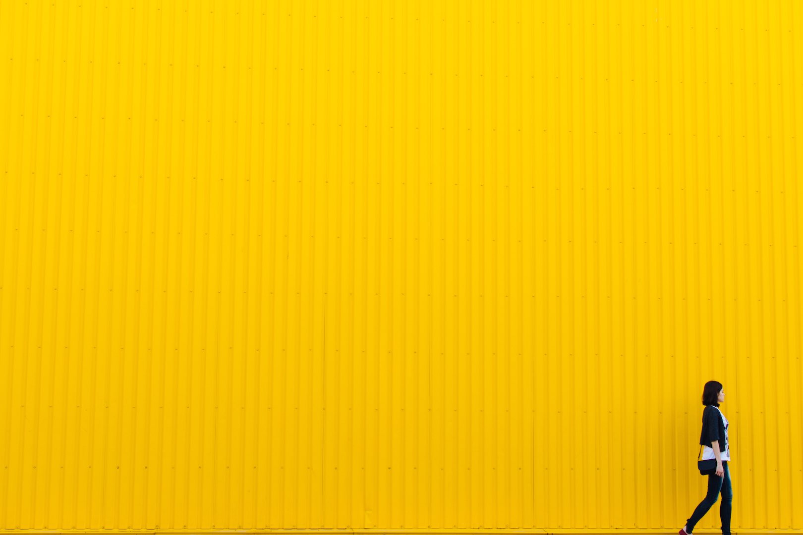 Mujer caminando frente a pared amarilla