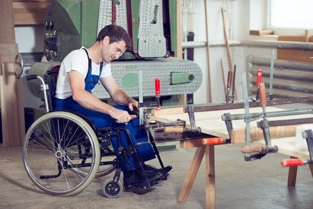 Persona usuaria  de silla de ruedas trabajando en un taller