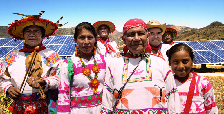 Indígenas delante de celdas solares