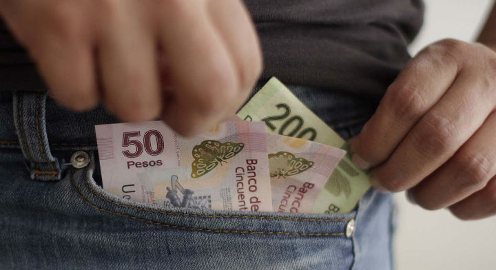 Una persona sacando unos billetes de su bolsillo