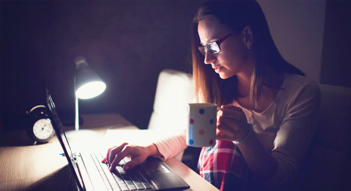 Mujer trabajando en su computadora en la obscuridad