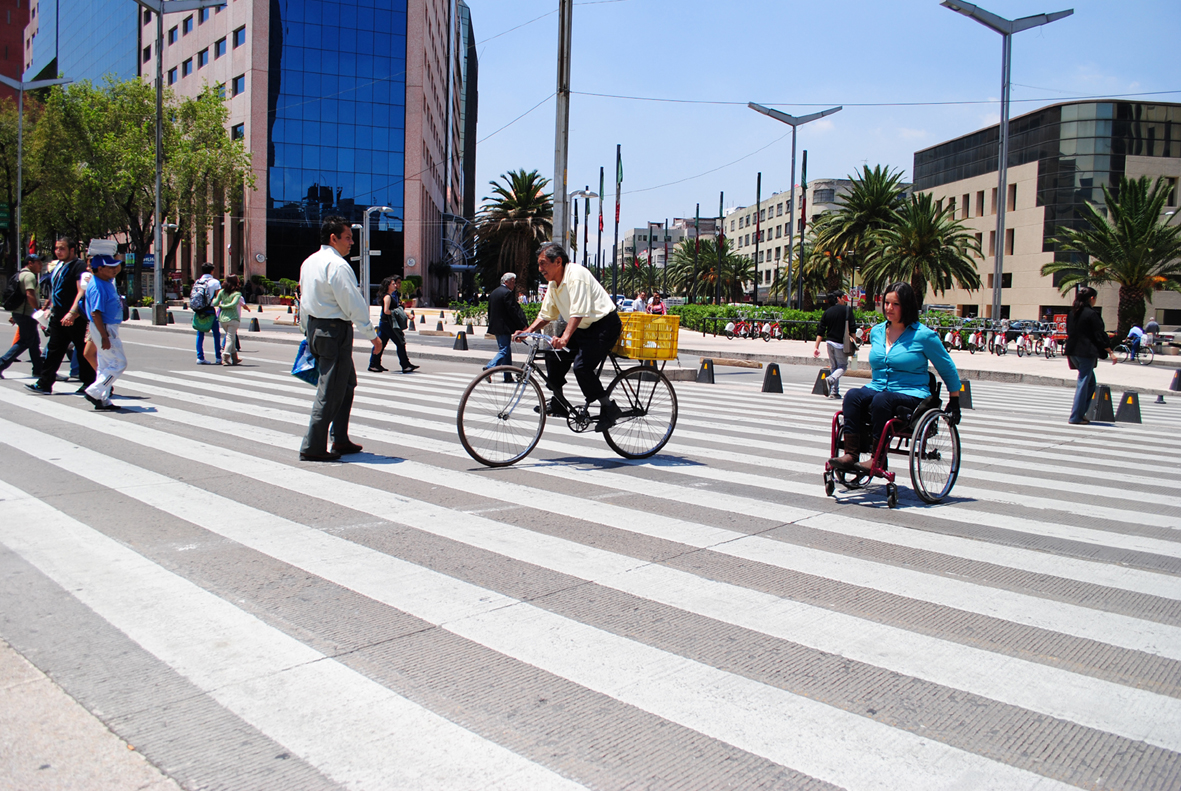Mujer joven en silla de ruedas, cruza una avenida 