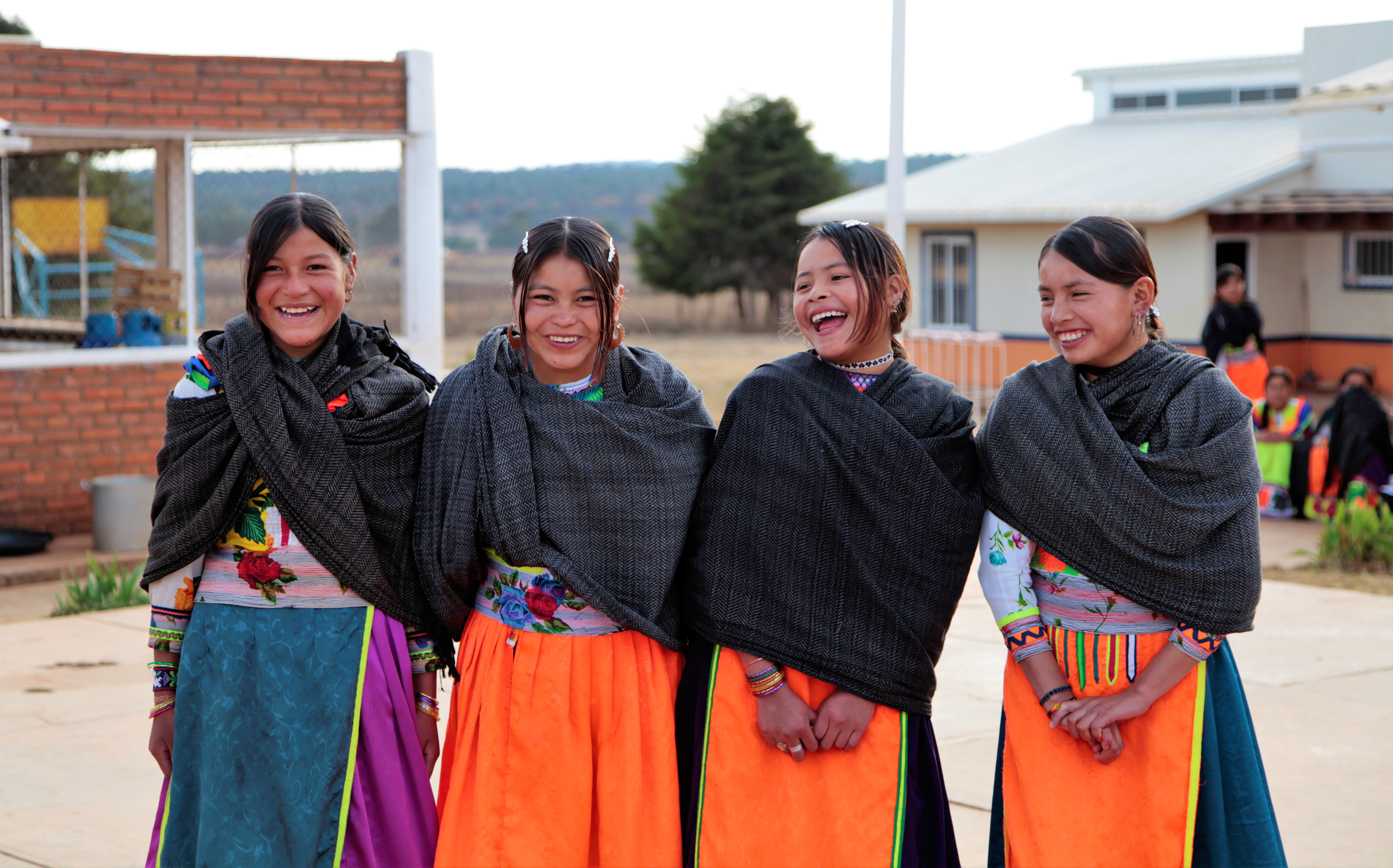 Cuatro chicas con vestido tradicional mexicano riéndose 