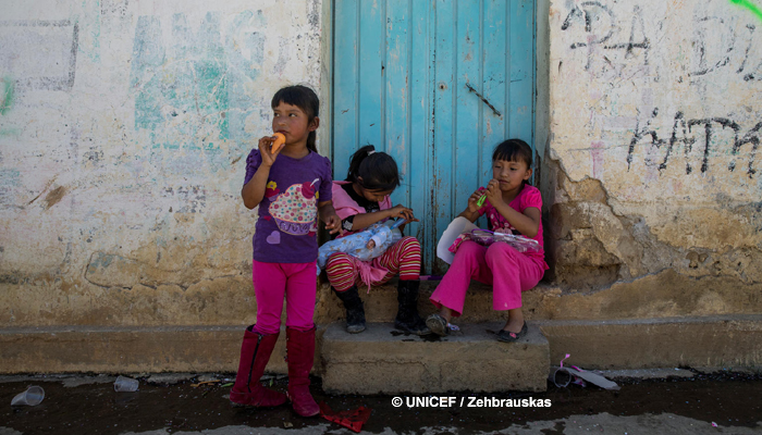Tres niñas en Puebla, en la puerta de su casa, juegan en la calle.