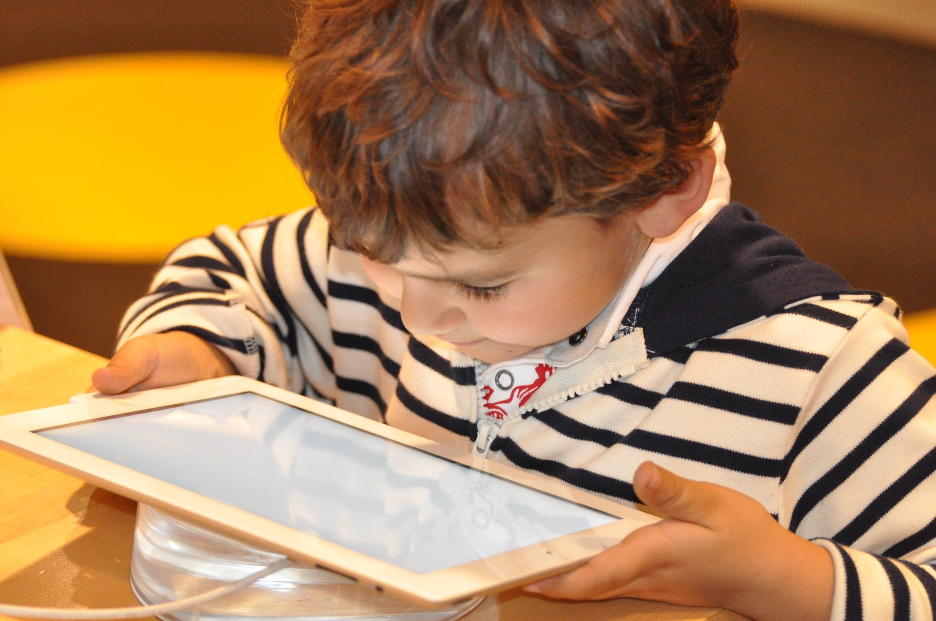 Niño concentrado en una tablet que sostiene con las manos