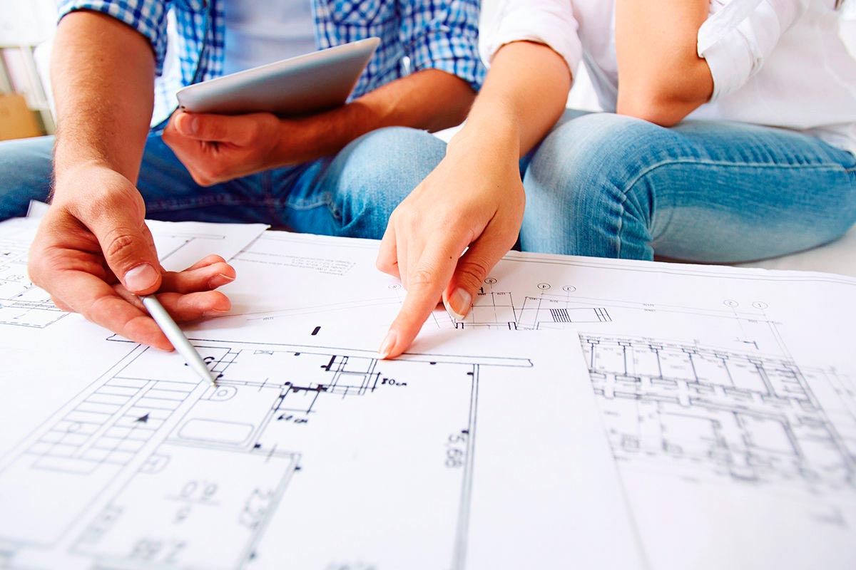 Se observan a dos personas acordando detalles sobre un plano de una construcción.