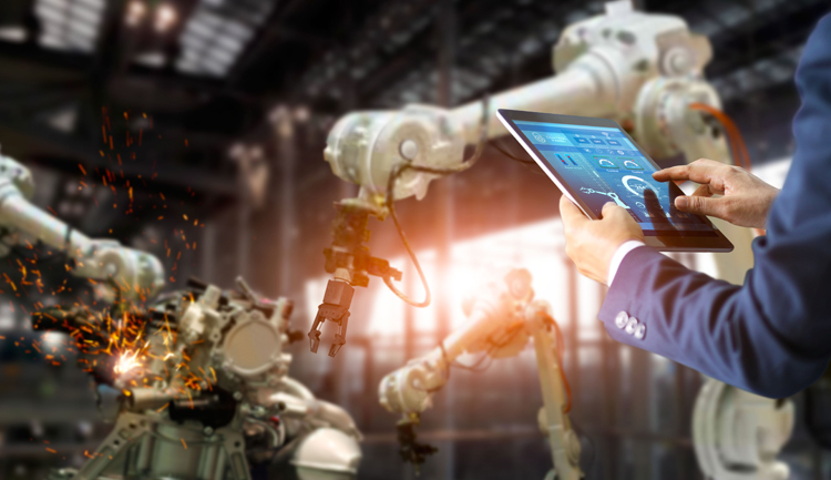 Ingeniero sostiene tableta mientras realiza proyecto de robótica que involucra a las industrias 4.0