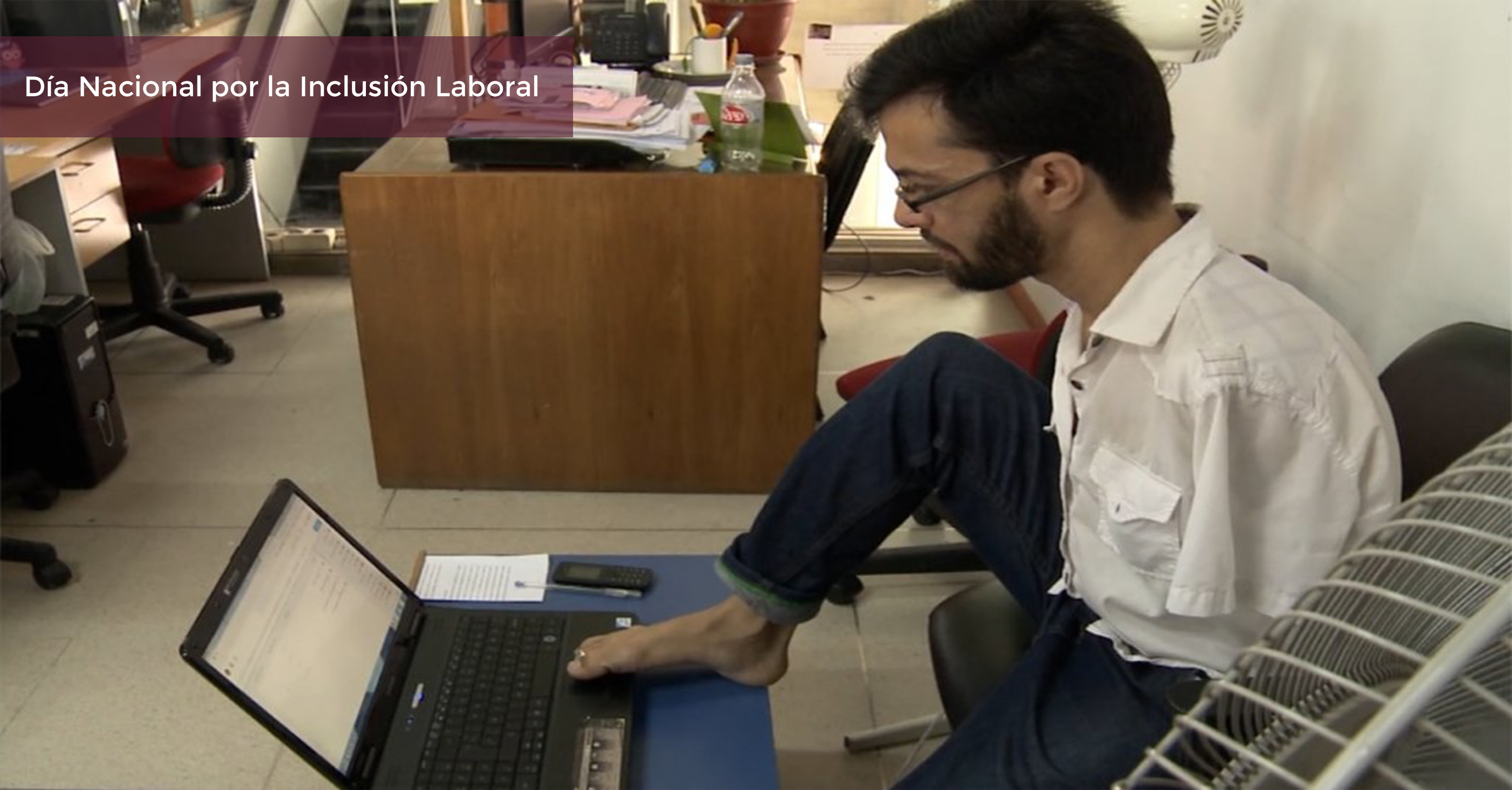 Joven sin brazos trabaja manejando la computadora con los pies en una oficina.
