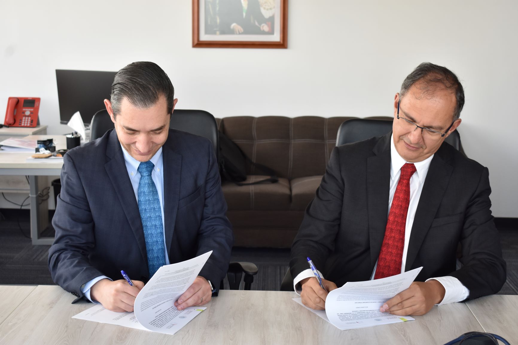 Fotografía del Director General de PROMTEL y el Secretario Ejecutivo de la SESNA firmando un documento