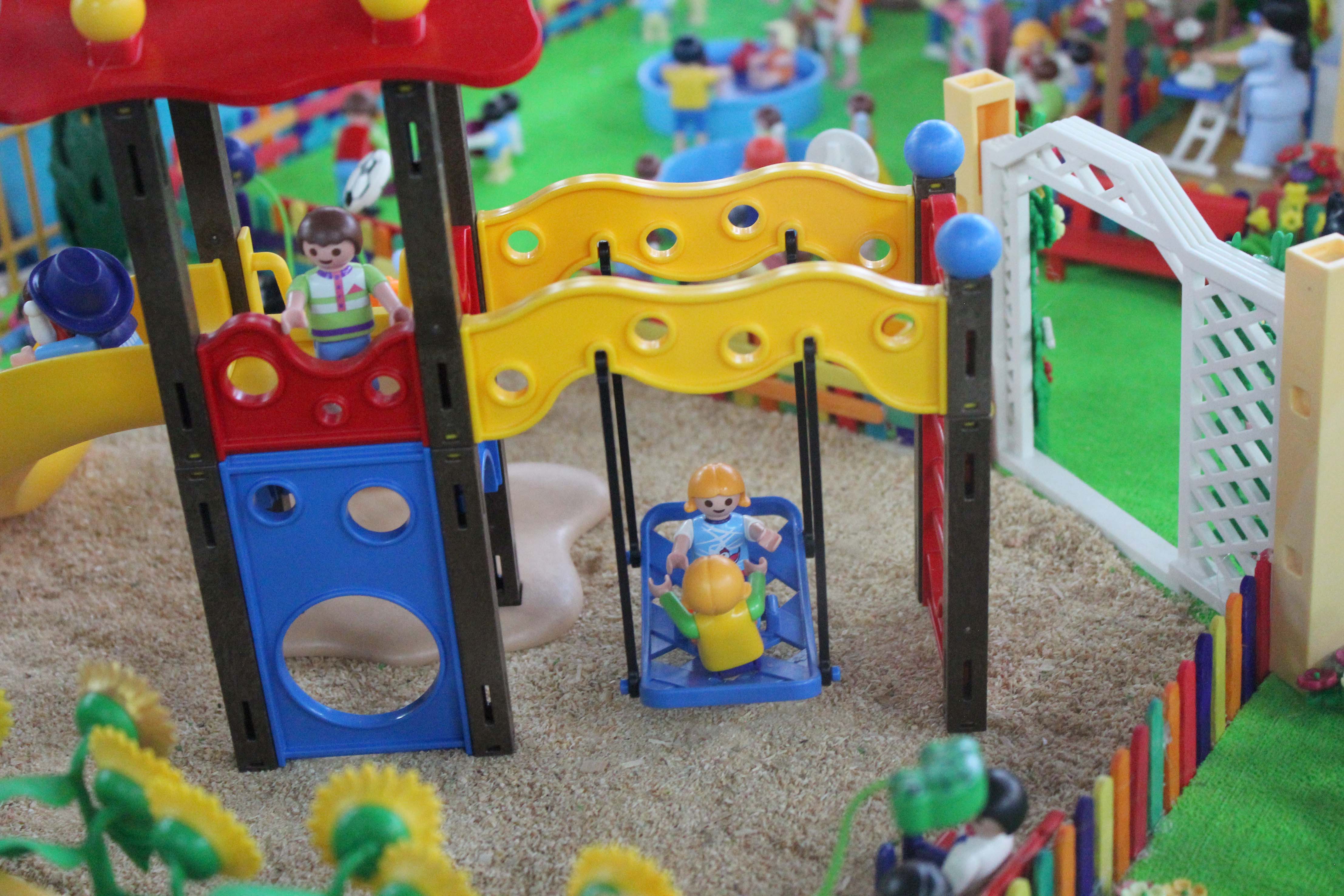 Maqueta de palymobil de niños y niñas en un parque de juegos.