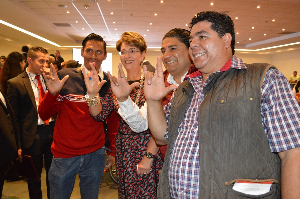 La Dra. Mercedes Juan, con un grupo de personas sordas todos con una señal en lengua de señas mexicana