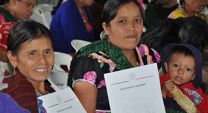 Mujeres durante entrega de  documentos agrarios e hijo en brazos 
