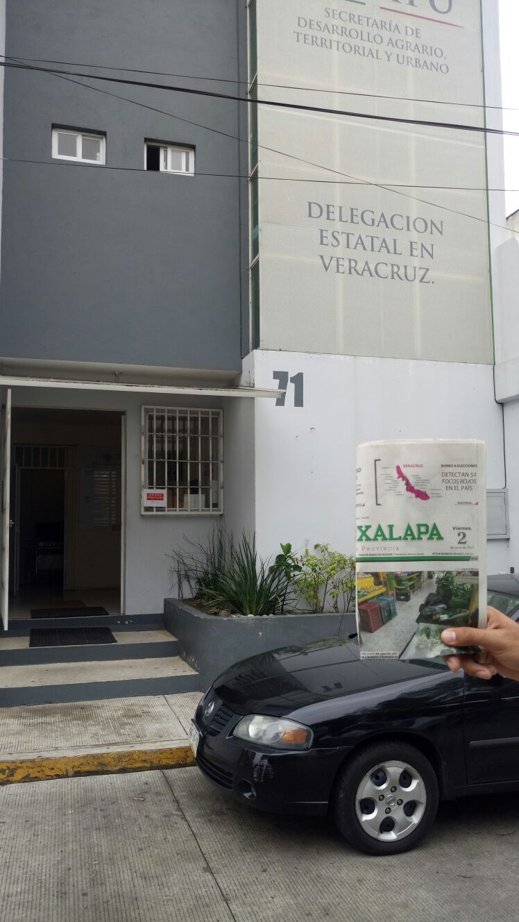 Personal de la delegación estatal de SEDATU en Veracruz ponen sellos de “Inmueble Verificado” en la puerta de entrada a sus oficinas. Para constatar que las acciones se realizaron este viernes se muestra el periódico del hoy.
