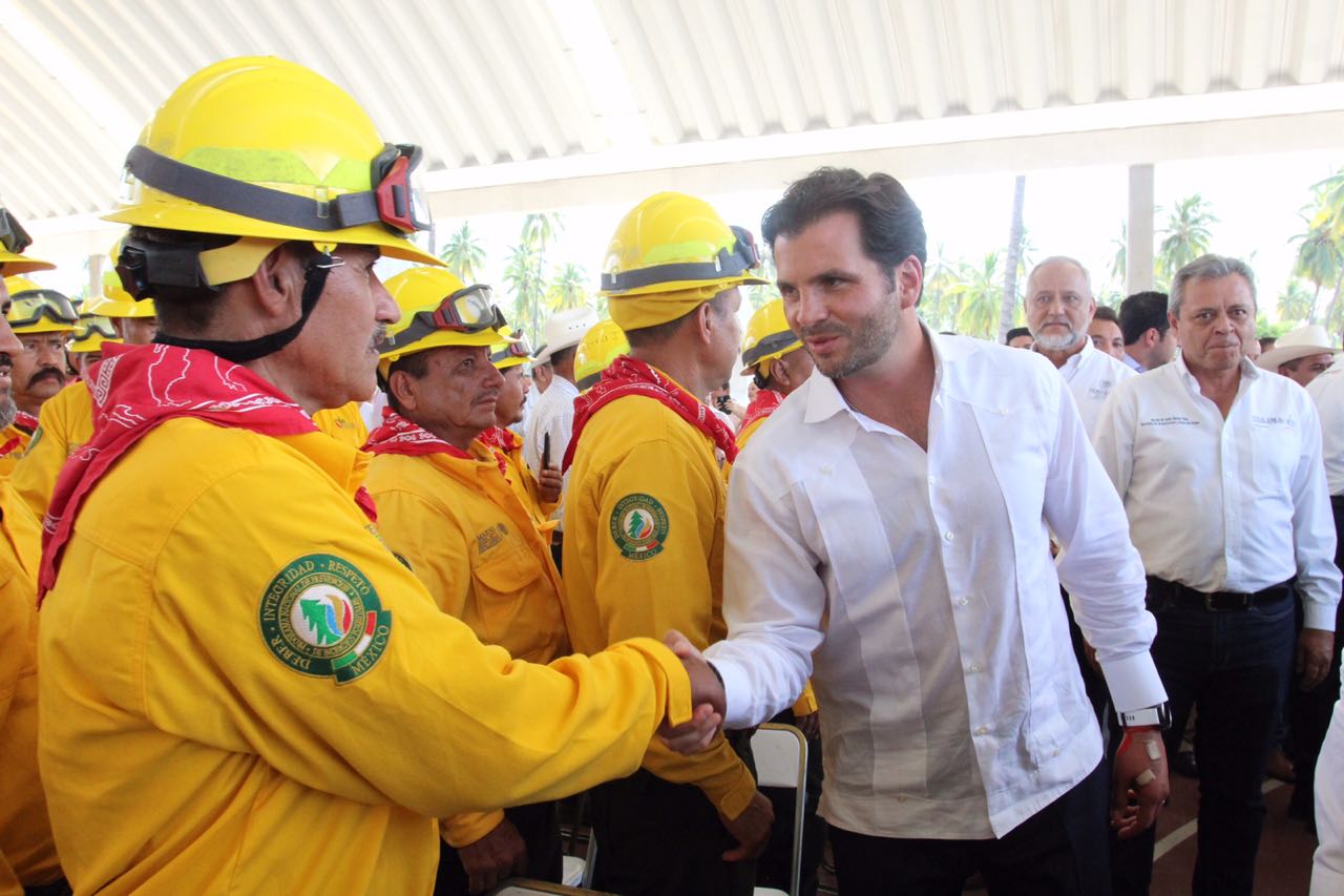 Secretario de Medio Ambiente y Recursos Naturales, Rafael Pacchiano Alamán, entre grupo de combatientes de incendios forestales saluda de mano a un integrante de éstos.