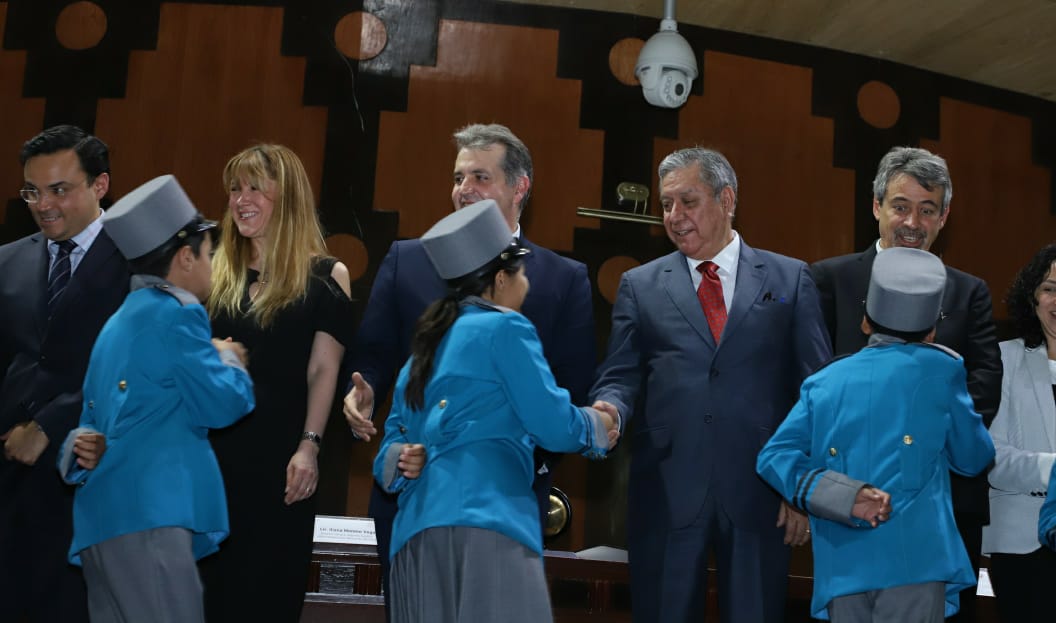 Fotografía donde se aprecia la fila de niñas y niños gritones que pasan saludando de mano a las autoridades del presidium