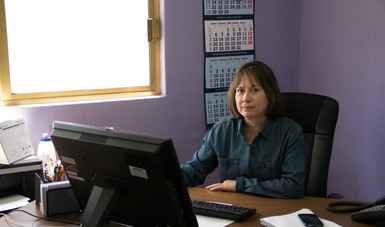 Una mujer sentada detrás de escritorio trabajando en una computadora.
