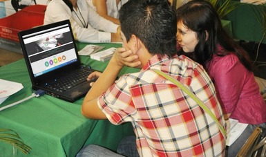 Dos personas jóvenes sentadas frente a una computadora.