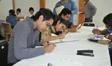 Jóvenes escribiendo en unas hojas durante un curso de capacitación.