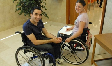 Personas con discapacidad en silla de ruedas viendo a la cámara sonriendo.