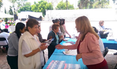 La licenciada Mónica San Juan entregando folletos a una señora en el stand de CONAMED