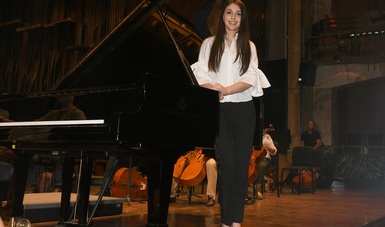 Daniela Liebman, recargada en un piano retrata a la cámara.