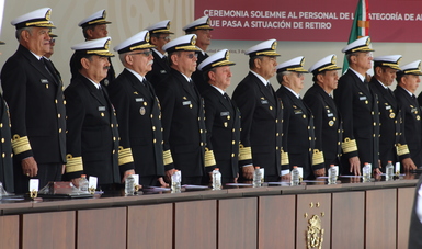 Personal de Almirantes del presidium vestidos de uniforme negro con galones dorados  en la parte de atrás leyenda: " Ceremonia solemne al personal de la categoría de Almirantes que pasan a situación de retiro"