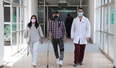 Paciente y médico del IMSS caminan sobre pasillos del hospital.