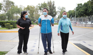 Paciente, familiar y médica caminan por la entrada del hospital.