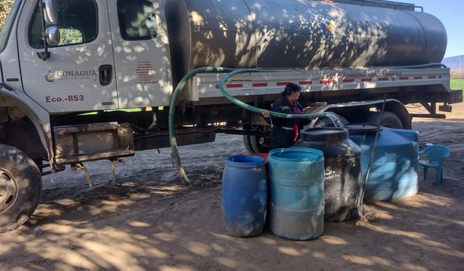 Brigadista PIAE suministra agua potable de un carro tanque, en tambos y tinacos de una comunidad vulnerable.