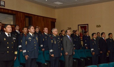 El Secretario del Trabajo acompañado por integrantes de la Maestría en Administración Militar del Colegio de la Secretaría de la Defensa Nacional, todos de pie, rindiendo honores a la bandera.
