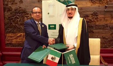 El Secretario del Trabajo y el Ministro de Trabajo de Arabia Saudita Mofarrej Alhoqubani, de pie saludándose, con el Acuerdo que firmaron en la mano.