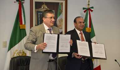 Dos hombres de pie, el Presidente de la CNDH, Luis Raúl González Pérez, y el Secretario del Trabajo, Alfonso Navarrete Prida, mostrando en las manos el Convenio firmado.